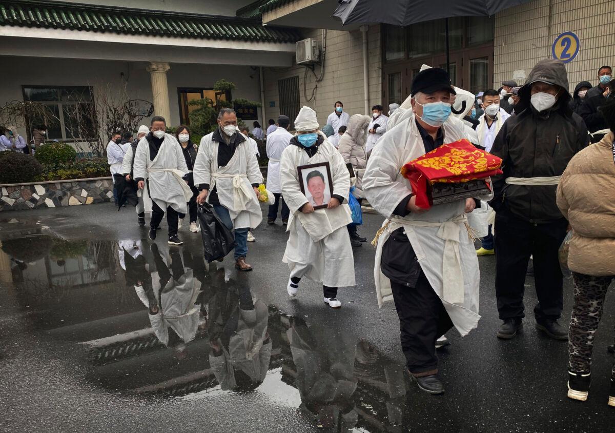 A mourner carries the cremated remains of a loved one as he and others wear traditional white funeral clothing during a funeral in Shanghai, China, in a file photo. (Kevin Frayer/Getty Images)
