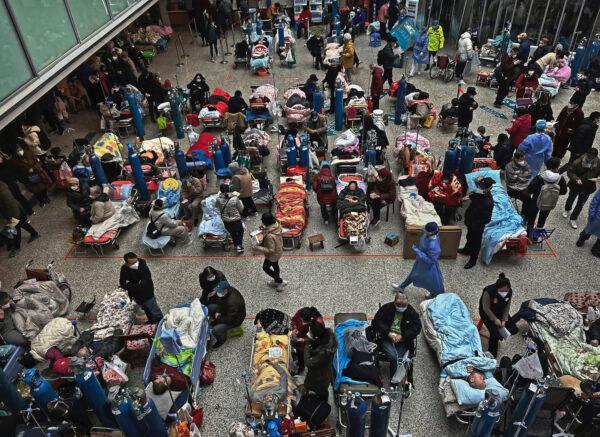 Patients on beds set up in the atrium area of a busy hospital are cared for by relatives and medical staff, in Shanghai on Jan. 13, 2023. (by Kevin Frayer/Getty Images)