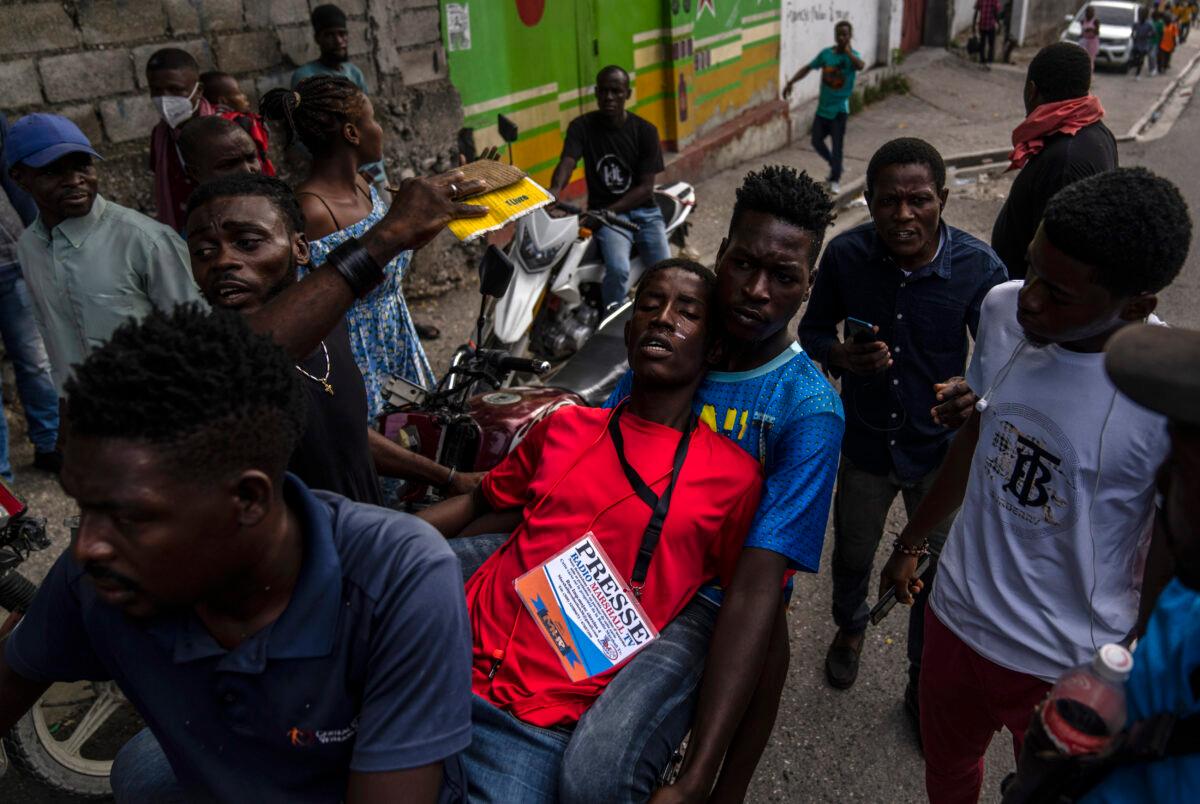 People help a journalist overcome by tear gas, launched by police during a protest over the death of journalist Romelson Vilsaint, in Port-au-Prince, Haiti, on Oct. 30, 2022. (Ramon Espinosa/AP Photo)
