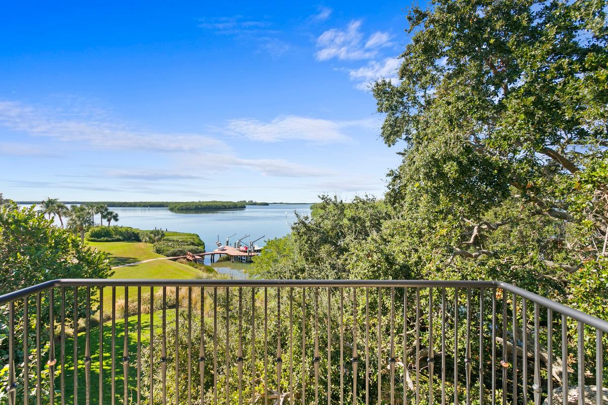 The view from the bedroom balcony, framed by manicured landscaping, takes in the boat dock, the nearby barrier islands, with the Gulf of Mexico beyond. (Courtesy of Sica Media)