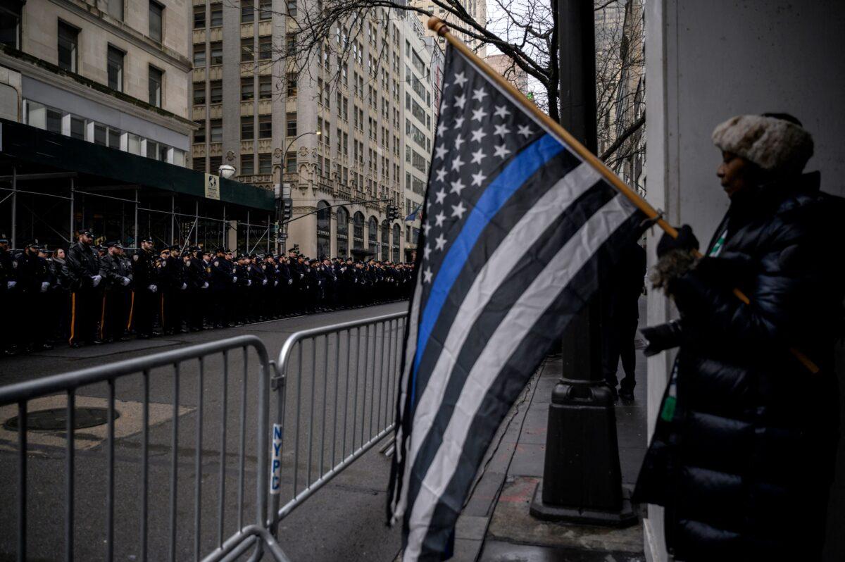 A person holds a thin blue line flag as New York police officers gather for the funeral of NYPD officer Wilbert Mora in New York on Feb. 2, 2022. (Ed Jones/AFP via Getty Images)