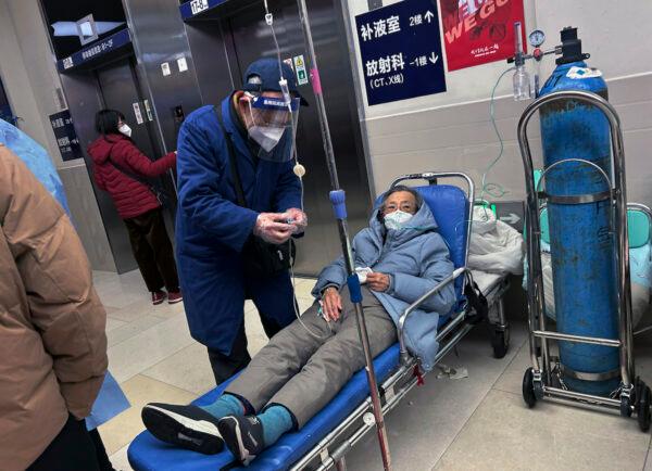 A man wears a face shield as he assists a loved one on a stretcher in the hallway of a busy hospital in Shanghai on Jan. 14, 2023. (Kevin Frayer/Getty Images)