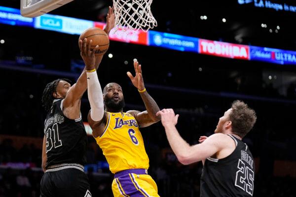 Los Angeles Lakers forward LeBron James, center, shoots as San Antonio Spurs forward Keita Bates-Diop, left, and center Jakob Poeltl defend during the first half of an NBA basketball game in Los Angeles on Jan. 25, 2023. (Mark J. Terrill/AP Photo)
