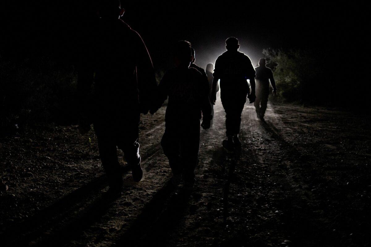 Asylum seeking migrants from Central America are followed by a border patrol vehicle as they walk down a dirt road after being smuggled across the Rio Grande river from Mexico into Roma, Texas, on Nov. 9, 2022. (Adrees Latif/Reuters)