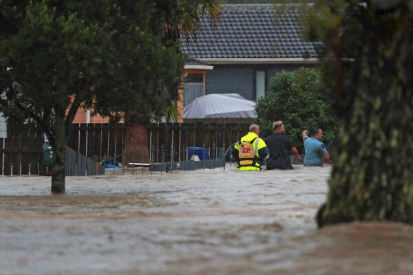 Emergency workers and a man wade through flood waters in Auckland, New Zealand, on Jan. 27, 2023. (Hayden Woodward/New Zealand Herald via AP)