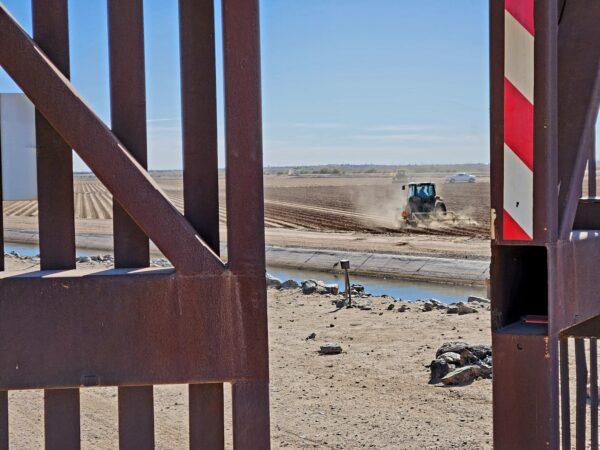 A farm tractor works the field just outside the border wall in San Luis, Ariz., on Jan. 27, 2023. (Allan Stein/The Epoch Times)