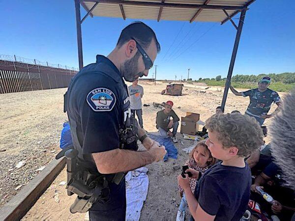 San Luis Police Lt. Marco Santana helps a group of children from Colombia at the border wall in late December 2022. (Courtesy of San Luis Police Lt. Marco Santana)