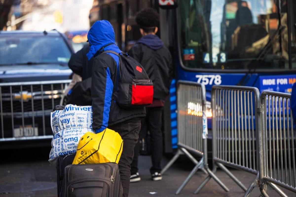 Illegal migrants carry their belongings to a bus after accepting relocation after being evicted from the Watson Hotel in New York City on Jan. 30, 2023. (Michael M. Santiago/Getty Images)