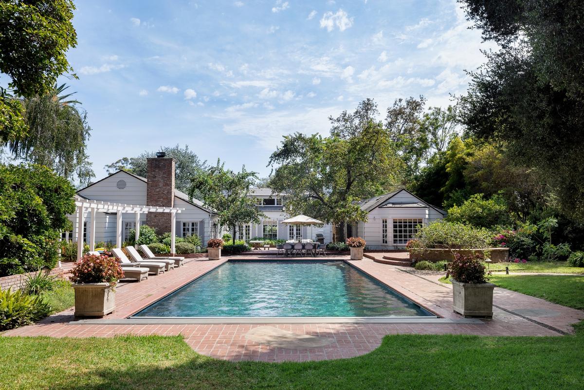 Viewed from the rear lawn, across the pool and past the pool house, this charming residence is an ideal place to raise a family or entertain. (Matt Wier for Sotheby’s International Realty)