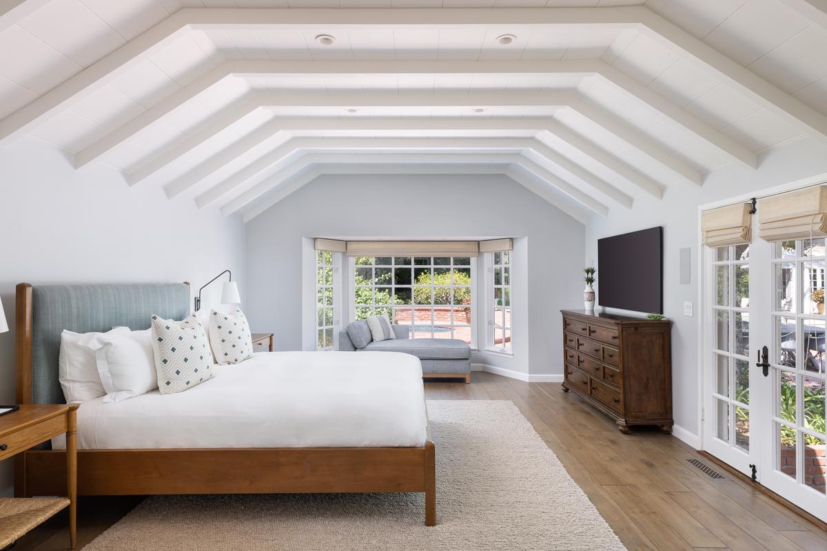 The two master suites, located on opposite sides of the ground floor, feature soaring vaulted ceilings with exposed beams, and direct access to the pool and hot tub area. (Matt Wier for Sotheby’s International Realty)