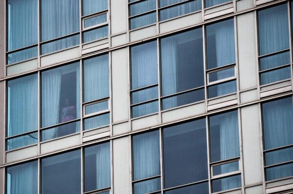 A person looks out the window of a room at a government-authorized COVID-19 quarantine hotel in Richmond, B.C., on Feb. 28, 2021. (Darryl Dyck/The Canadian Press)