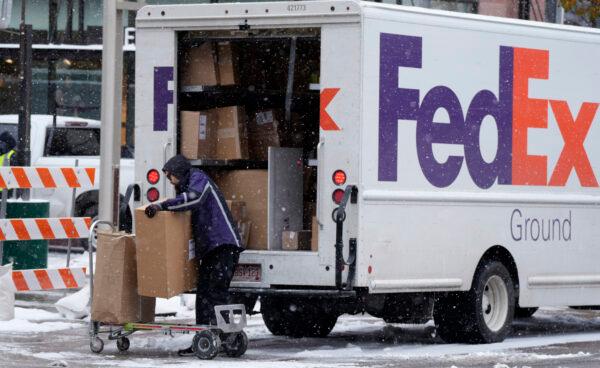 A FedEx worker places a package on a trolley after a cold front packing subfreezing temperatures and light snow swept over the intermountain in Denver on Nov. 17, 2022. (David Zalubowski/AP Photo)