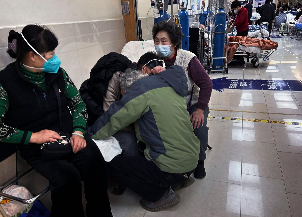 A man hugs an elderly relative in the hallway of a busy emergency room at a hospital in Shanghai on Jan. 14, 2023. (Kevin Frayer/Getty Images)