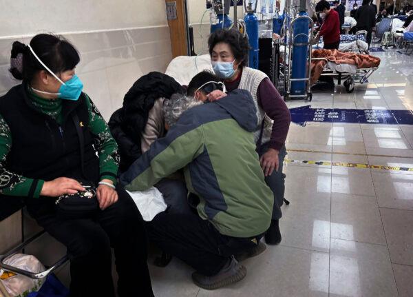 A man hugs an elderly relative as he and others offer support as she is cared for in the hallway of a busy emergency room at a hospital in Shanghai, China, on Jan. 14, 2023. (Kevin Frayer/Getty Images)