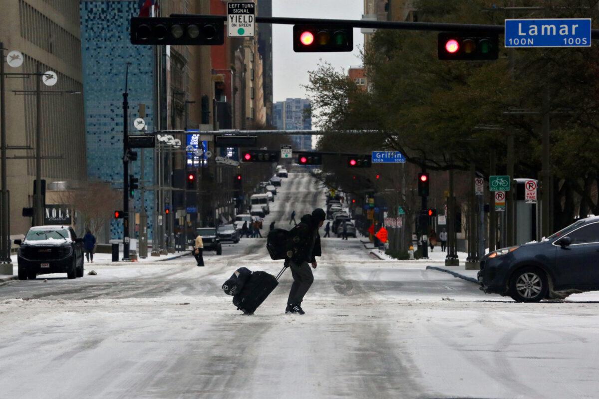 Pedestrians walk across icy roads as a cold weather front moves through Dallas on Jan. 31, 2023. (Shelby Tauber/Reuters)