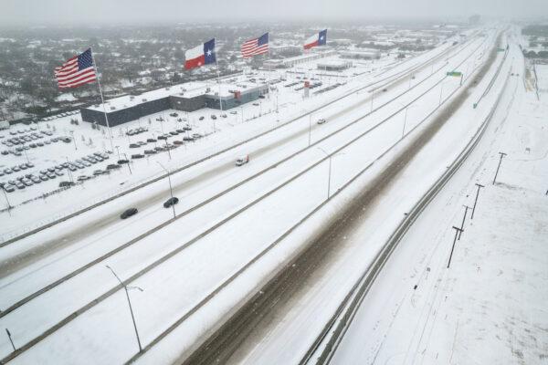 U.S. and Texas state flags fly over a Nissan car dealership as light traffic moves through snow and ice on U.S. Route 183 in Irving, Texas, on Feb. 3, 2022. (John Moore/Getty Images)