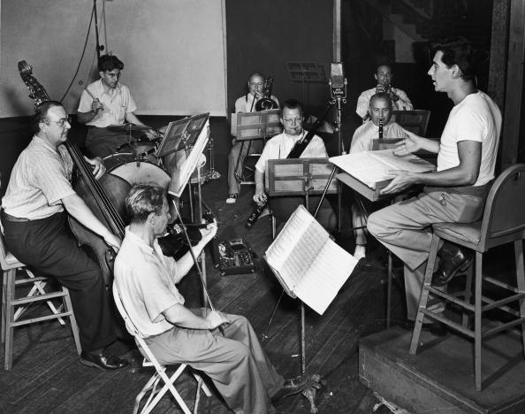 Composer and conductor Leonard Bernstein conducting a small orchestra from a podium during a recording session for RCA Victor records. (Hulton Archive/Getty Images)