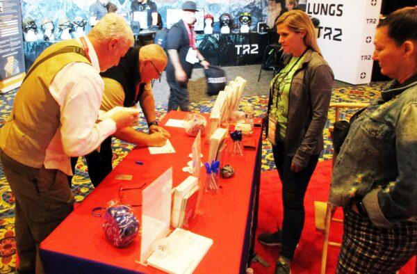 Mark Lorrin (Left), and John Pascale (Center Left), both of SKAB Engineering write letters of gratitude to the families of fallen veterans during the 2023 SHOT Show in Las Vegas, Nev. as Dr. Tracy Uribe (Center Right) and Amy Cotta (Right), both of Memories of Honor, watch. (Michael Clements/The Epoch Times)