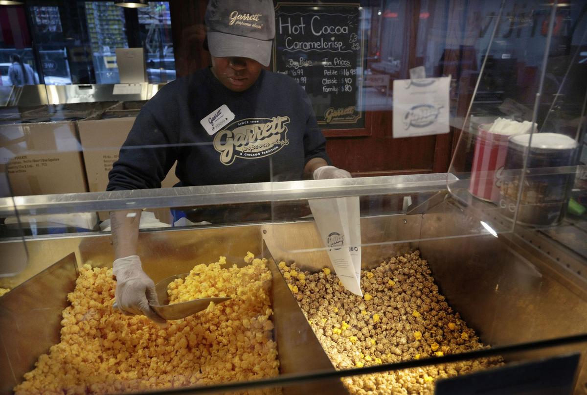 Clerk Kendra Hudson prepares to fill up a customer's popcorn bag at Garrett Popcorn Shops’ flagship store on Michigan Avenue on Jan. 12, 2023, in Chicago. (Antonio Perez/Chicago Tribune/TNS)