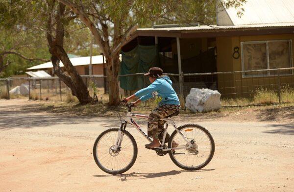 10-year-old Cody Shaw rides a bike in the street outside the home of his aunty and indigenous campaigner Barbara Shaw in the Mount Nancy town camp at Alice Springs in Australia's Northern Territory state on Oct. 13, 2013. (Greg Wood/AFP via Getty Images)