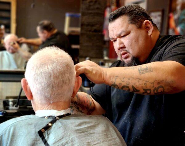 Luis Bermudez (R), the owner of This Old Barbershop in Phoenix, Ariz., puts the final touches on customer Jacob Silverest on Jan. 26, 2023. (Allan Stein/The Epoch Times)
