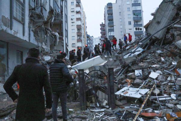 People and rescue teams try to reach trapped residents inside collapsed buildings in Adana, Turkey, on Feb. 6, 2023. (IHA agency via AP)