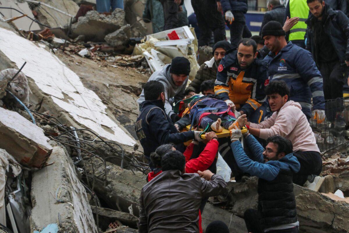 People and emergency teams rescue a person on a stretcher from a collapsed building in Adana, Turkey, on Feb. 6, 2023. (IHA agency via AP)