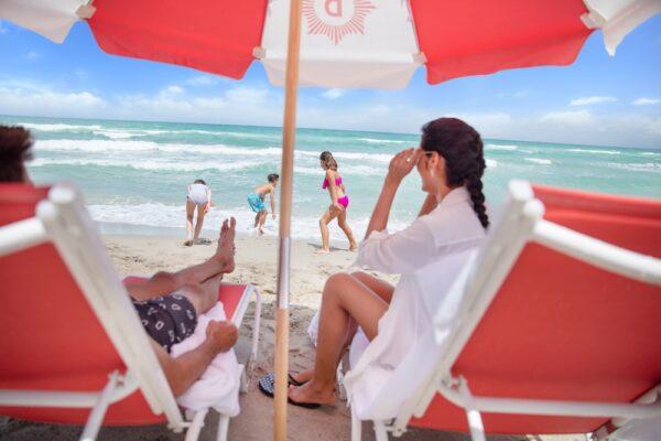 A couple relaxes on the beach while their children play in the sand and surf. (Courtesy of the Diplomat Beach Resort)