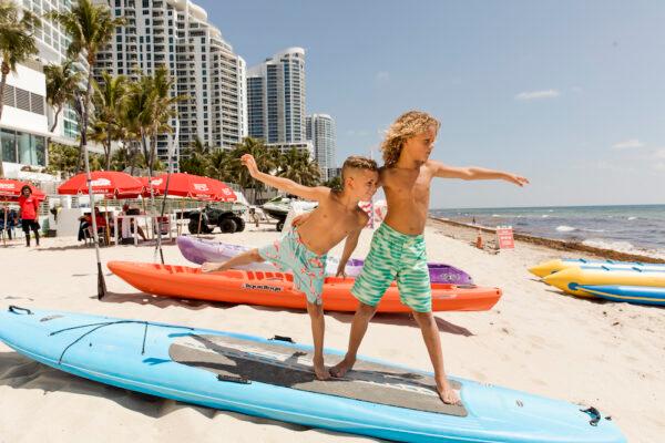 Kids enjoy playing on a stand-up paddle board on the beach. (Courtesy of the Diplomat Beach Resort)
