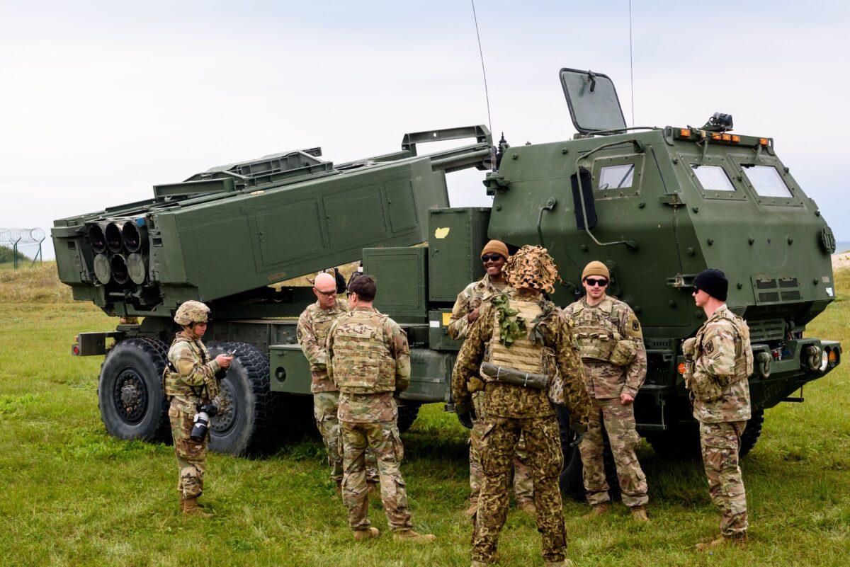 Military personnel stand in front of a High Mobility Artillery Rocket System (HIMARS) during the military exercise Namejs 2022 in Skede, Latvia, on Sept. 26, 2022. (Gints Ivuskans/AFP via Getty Images)