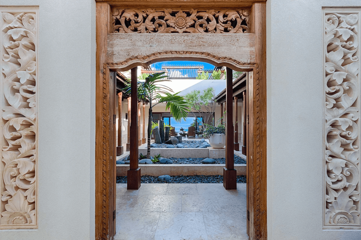 The open courtyard and second-level deck features intricate, hand-carved woodwork and manicured native plants and trees. (Courtesy of Sotheby’s Concierge Auction)