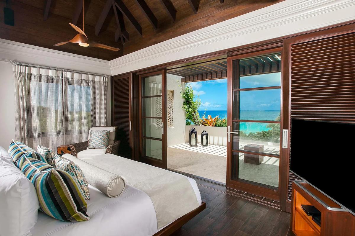 This guest bedroom features a soaring vaulted ceiling and sliding glass doors opening onto the deck that overlooks the beach. (Courtesy of Sotheby’s Concierge Auction)
