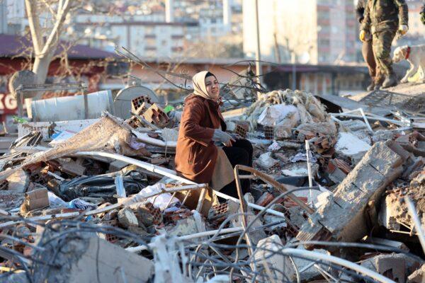 A woman sits on the rubble of a destroyed building in Kahramanmaras, southern Turkey, a day after a 7.8-magnitude earthquake struck the country's southeast, on Feb. 7, 2023. (Adem Altan /AFP via Getty Images)