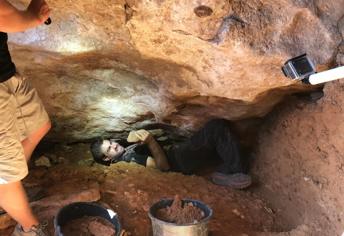 Professor Martín Lerma, of the University of Murcia, excavates a stone wall that appears to be a "roof" of the cave. (Courtesy of University of Murcia)
