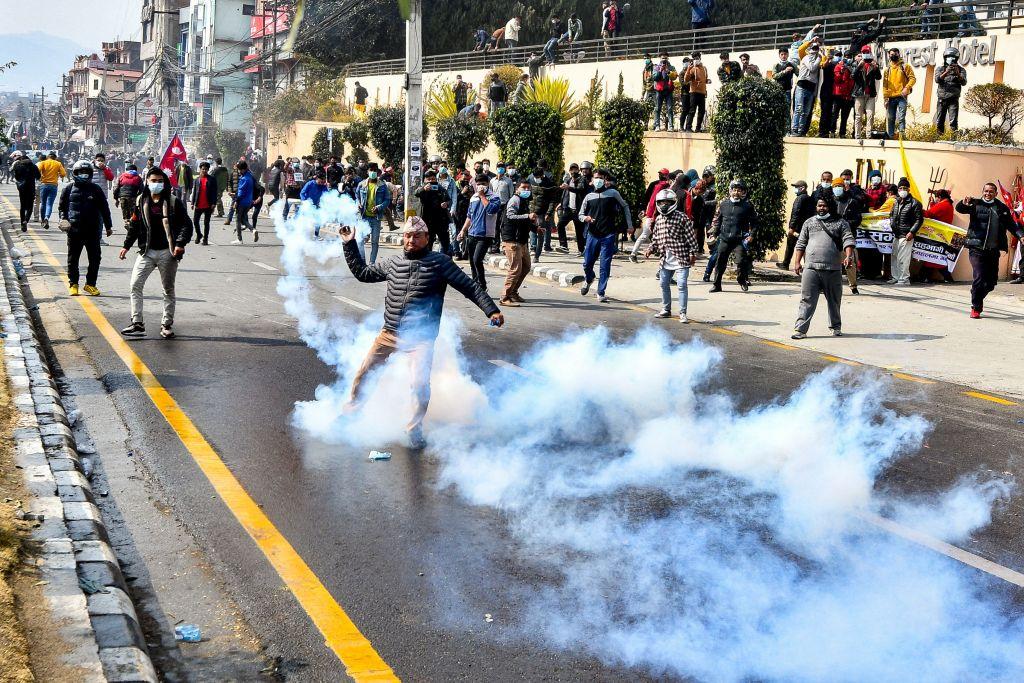 A demonstrator returns a tear gas cannister towards the police during a protest against the proposed grant agreement from America under the Millennium Challenge Corporation (MCC), in Kathmandu on February 24, 2022. (Prakash Mathema/AFP via Getty Images)