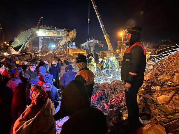 Local residents look on as rescue efforts continue into the night in Hatay’s Iskenderun district on Feb. 8, 2023. (Ercan Koc for The Epoch Times)