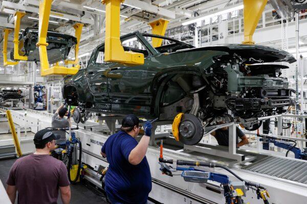 Employees work on an assembly line at startup Rivian Automotive's electric vehicle factory in Normal, Ill., on April 11, 2022. (Kamil Krzaczynski/Reuters)