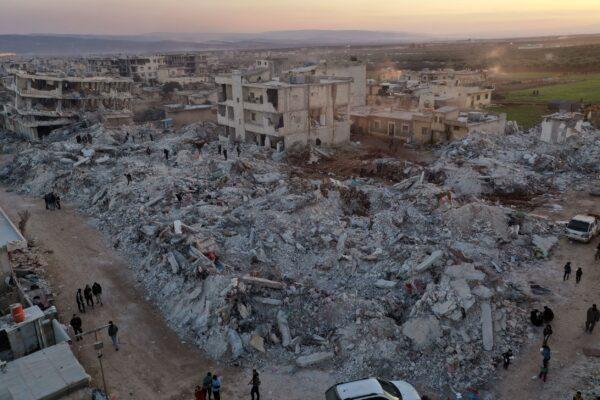 People walk past collapsed buildings following a devastating earthquake in the town of Jinderis, Syria, on Feb. 9, 2023. (Ghaith Alsayed/AP Photo)