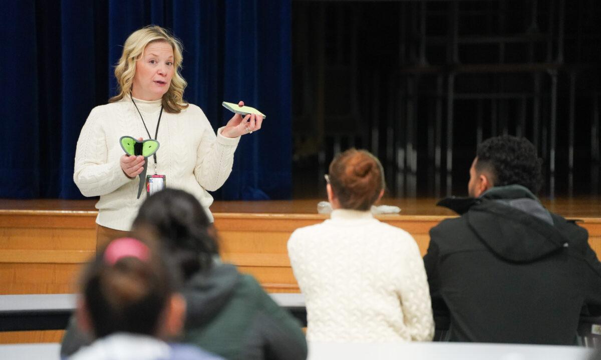 Middletown School District Superintendent Amy Creeden demonstrates a Yondr pouch at a presentation to parents at Presidential Park Elementary School in Middletown, N.Y., on Feb. 7, 2023. (Cara Ding/The Epoch Times)