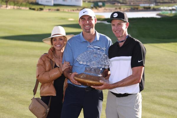 Scottie Scheffler of the United States celebrates with the trophy alongside wife Meredith Scudder (L) and caddie Ted Scott (R) after winning during the final round of the WM Phoenix Open at TPC Scottsdale in Scottsdale, Ariz., on Feb. 12, 2023. (Maddie Meyer/Getty Images)