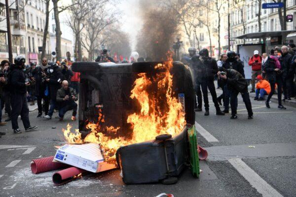 Onlookers gather around a car in a fire on the sidelines of a demonstration on the fourth day of nationwide rallies organised since the start of the year against a deeply unpopular pensions overhaul, in Paris, on Feb. 11, 2023. (Bertrand Guay/AFP via Getty Images)