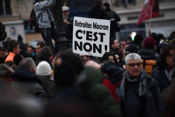 A protester holds a placard reading "Macron pensions, it's no!" during a demonstration on the fourth day of nationwide rallies organised since the start of the year against a deeply unpopular pensions overhaul, in Paris, on Feb. 11, 2023. (Christophe Archambault/AFP via Getty Images)