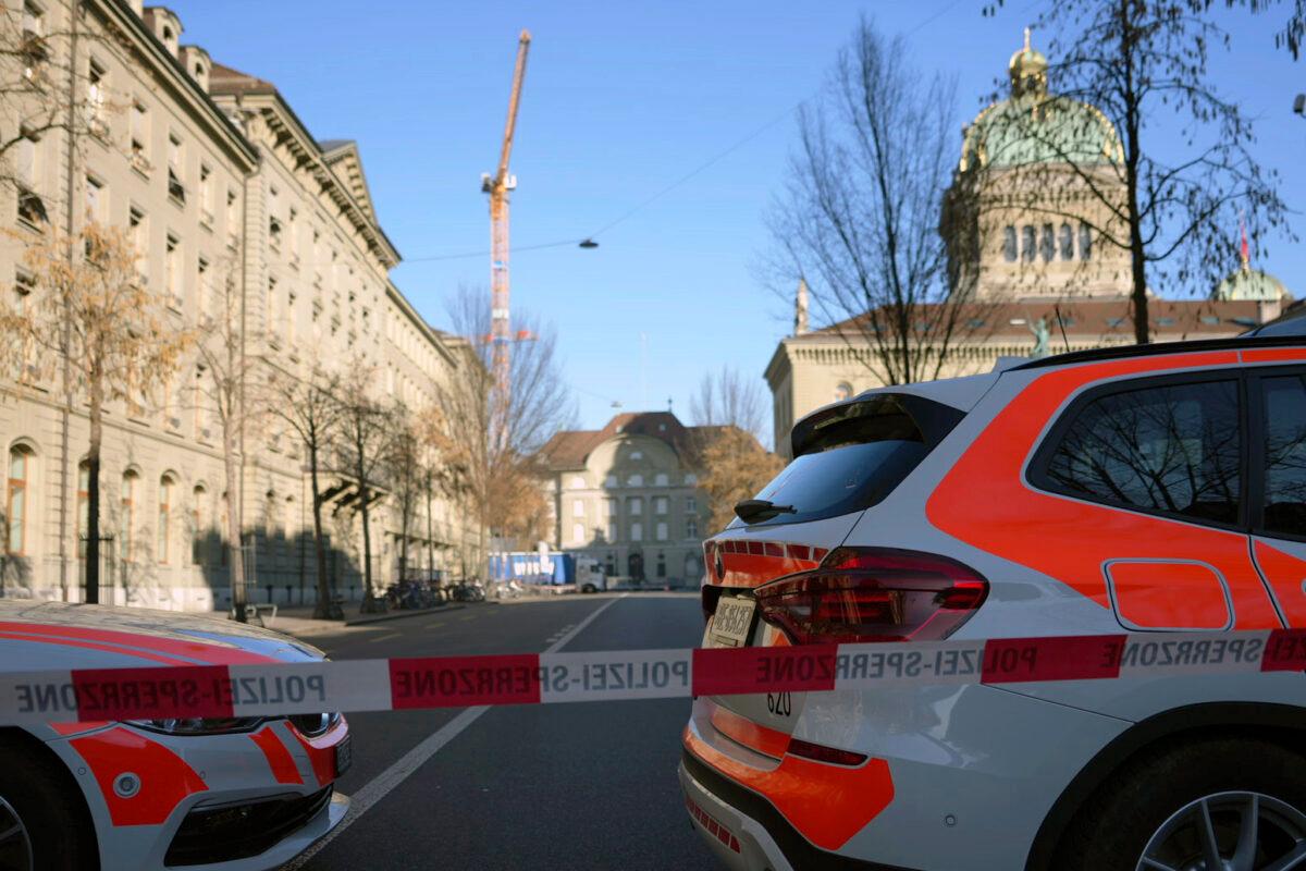 Police vehicles are parked in front of the Swiss Parliament, the Bundeshaus, during a large-scale operation of the Bern police, where several buildings were evacuated and the Bundesplatz and some streets around were widely cordoned off, in Bern, Switzerland, on Feb. 14, 2023. (Manuel Lopez/Keystone via AP)