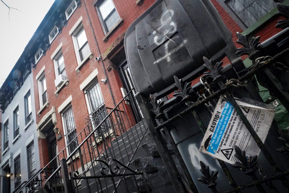 A caution sign for rodenticide is posted on a fence next door to a building, second from left, owned by New York Mayor Eric Adams in the Bedford-Stuyvesant neighborhood of the Brooklyn borough of New York on Dec. 7, 2022. (Bebeto Matthews/AP Photo)