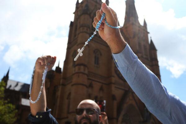 Catholic worshippers signal toward protesters outside St. Mary’s Cathedral during the pontifical requiem Mass for Cardinal George Pell in Sydney, Australia, on Feb. 2, 2023. (Lisa Maree Williams/Getty Images)