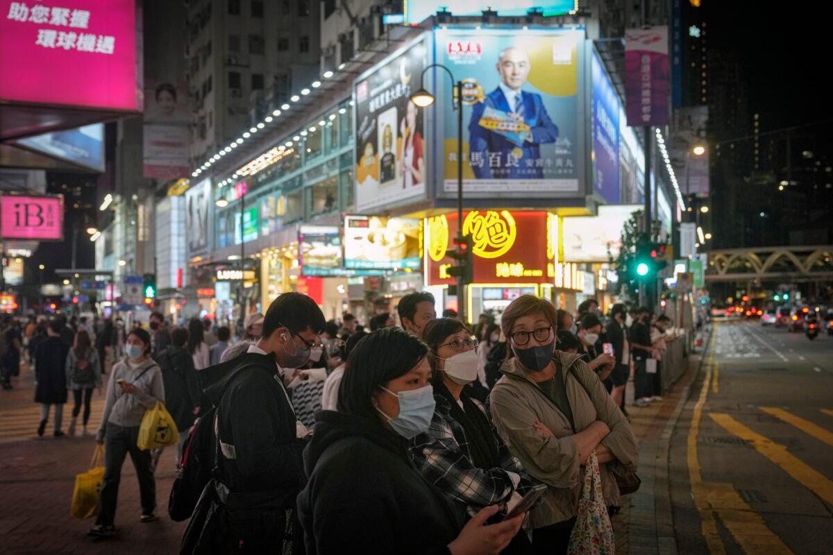 People wearing masks wait to cross a traffic intersection at the Causeway Bay shopping district in Hong Kong on Feb. 7, 2023. (Andy Wong/AP Photo)
