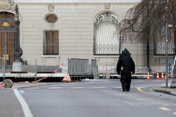 An explosives expert walks in front of the Swiss Parliament, the Bundeshaus, during the large-scale operation of the Bern police, where several buildings were evacuated and the Bundesplatz and some streets around were widely cordoned off, in Bern, Switzerland, on Feb. 14, 2023. (Manuel Lopez/Keystone via AP)