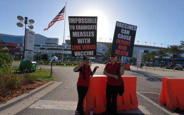  Two women hold signs raising awareness about the possibility of vaccine injuries at the 2019 Daytona 500 NASCAR race in Daytona Beach, Fla. (Courtesy of PeopleOverPolitics.org)
