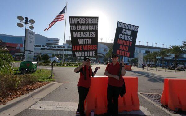 Two women hold signs raising awareness about the possibility of vaccine injuries at the 2019 Daytona 500 NASCAR race in Daytona Beach, Fla. (Courtesy of PeopleOverPolitics.org)