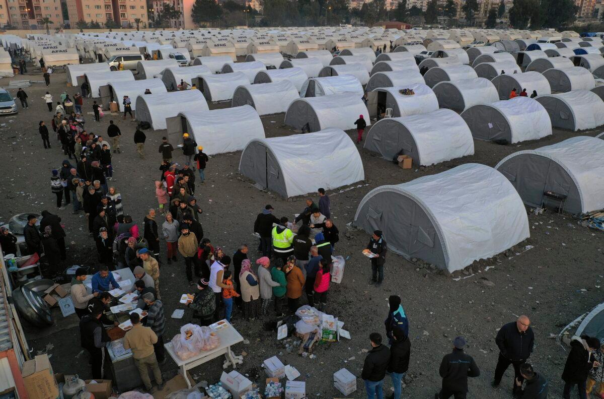 People who lost their houses in the devastating earthquake lineup to receive food at a makeshift camp in Iskenderun city, southern Turkey, on Feb. 14, 2023. (Hussein Malla/AP Photo)